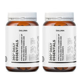 Zwei Flaschen Daluma 360 DAILY ESSENTIALS SUPPLEMENT DOUBLE mit weißen Etiketten und orangefarbenen Verschlüssen, nebeneinander auf weißem Hintergrund. Der Text auf dem Etikett ist verschwommen und unleserlich.