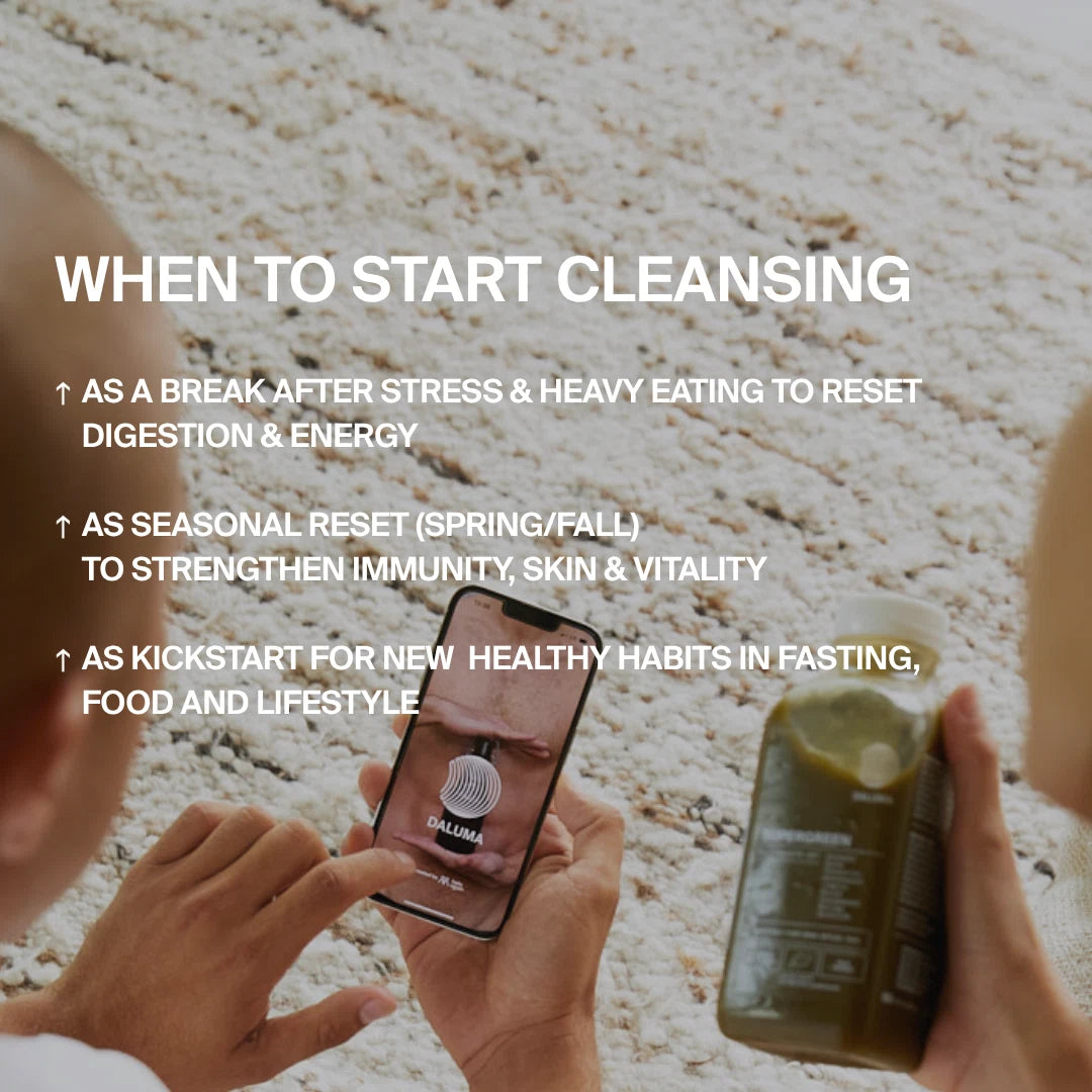 Jemand hält eine DALUMA BESSERE SAFTKUR PLUS - 7 TAGE grüne Saftflasche in der Hand, während er eine Cleanse-App benutzt. Das Bild zeigt den idealen Zeitpunkt für eine Saftkur: nach Stress, übermäßigem Essen, saisonal oder um gesunde Gewohnheiten zu beginnen. Ein leichter Teppich ist sichtbar.