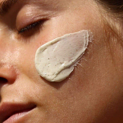 Eine Nahaufnahme des Gesichts einer Person mit geschlossenen Augen, auf deren Wange die DEEP HYDRATION FEUCHTIGKEITSMASKE von DALUMA aufgetragen ist - eine dicke, cremige Maske aus natürlichen Zutaten.