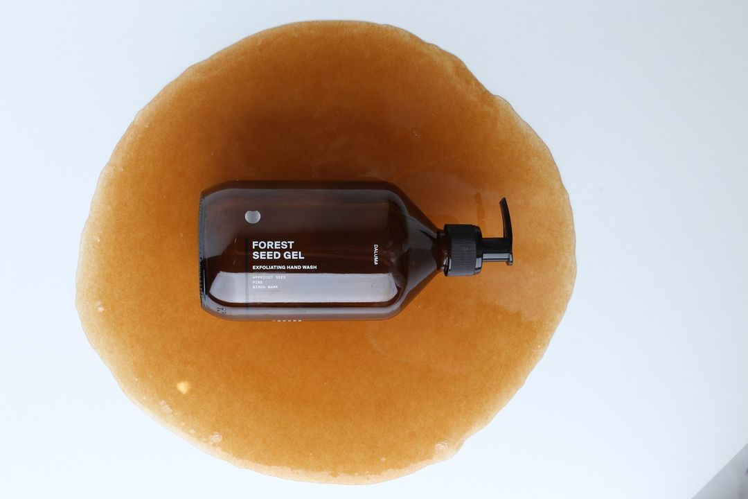 Eine braune Pumpflasche mit DALUMA FOREST SEED GEL HAND WASH steht auf einer Lache aus karamellfarbenem Gel und hebt dieses Handwaschmittel mit natürlichen Inhaltsstoffen für sanfte Hautpflege hervor.