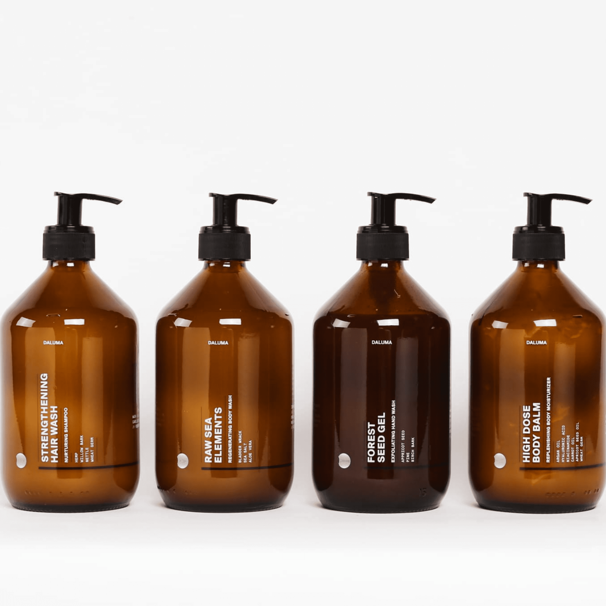 Vier braune DALUMA-Pumpflaschen mit weißer Schrift stehen vor einem weißen Hintergrund, darunter FOREST SEED GEL HAND WASH und andere Hautpflegeprodukte wie Shampoo und Duschgel, die alle mit natürlichen Inhaltsstoffen hergestellt werden.