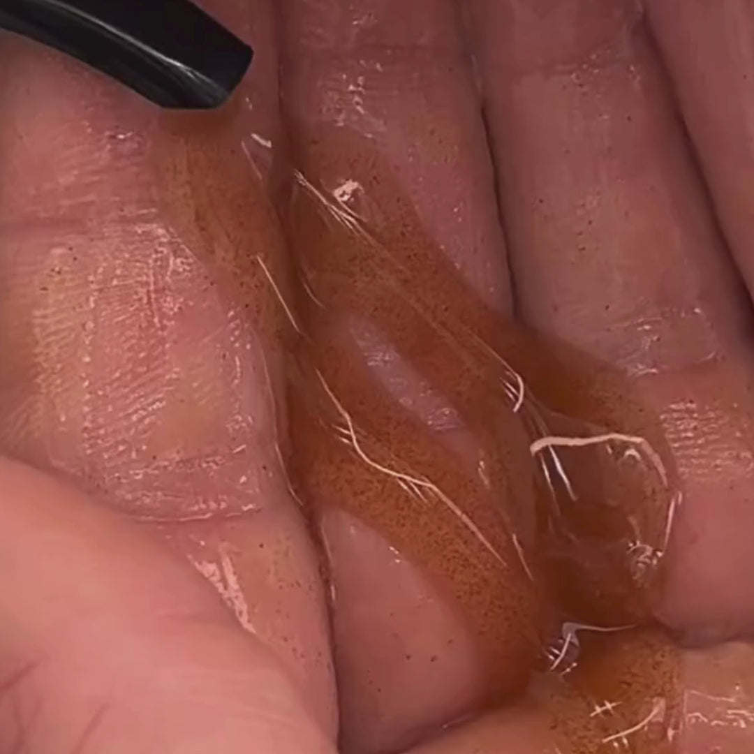 Nahaufnahme einer Hand mit einer kleinen Menge des bräunlichen, durchscheinenden Gels von Daluma CLEANSE COUPLE, das aus einer schwarzen Düse auf die Handfläche aufgetragen wird.