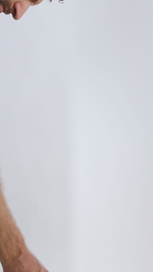 Eine Nahaufnahme des Arms und des unteren Teils des Gesichts einer Person vor einem schlichten, hellen Hintergrund, auf dem Dalumas SYM-BIOTIC 23/100 BILLION DARMBAKTERIEN zu sehen ist.